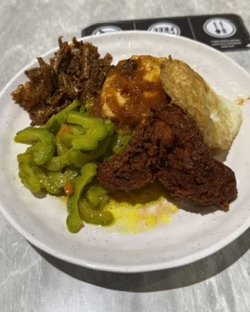 A real plate of rice, sambal, fried chicken, egg and greens, photographed on the table exactly as it was eaten.
